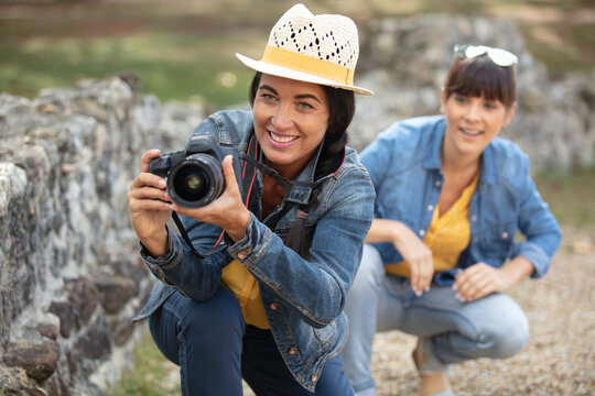 Two Female Photographer Crouching Near A Wall