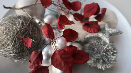 close-up of a beautiful twig with red leaves on silver christmas decoration plate with a sunbeam