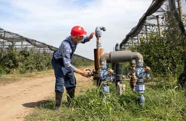 Farmer repairing valve irrigation system in orchard