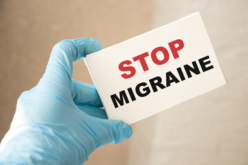 Doctor holding a card with Stop Migraine, medical concept