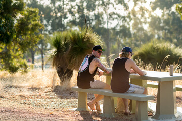 Back view of two guys sitting at a picnic table in a rural setting