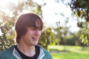 Young man with hair in his eyes backlit with sun flare