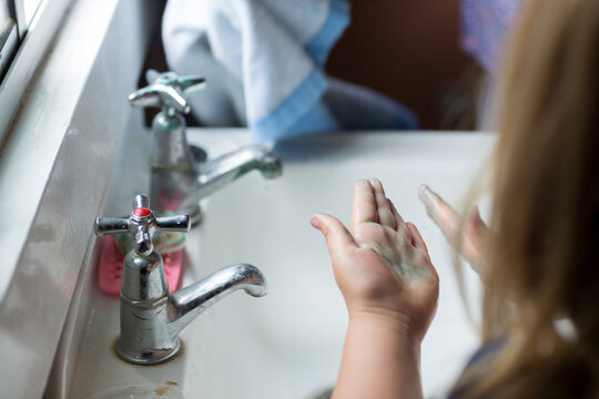 Child washing hands at old-fashioned sink
