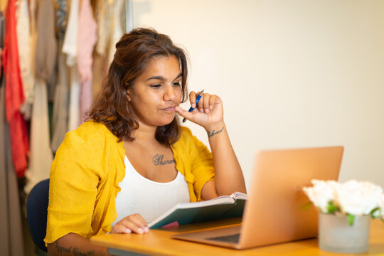young woman sitting at desk consulting her laptop and diary