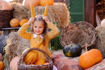Portrait of a cute beautiful girl at the harvest festival on the farm. Happy child celebrates thanksgiving day. Autumn September October November. 