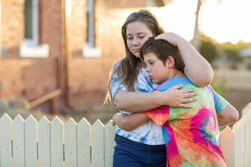 Two kids embracing outside an old house