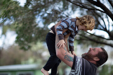 Man lifting young child in the air outside