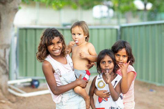 Portrait Of Smiling Children With Lollipops Standing In Backyard