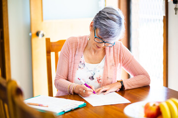 Middle aged woman signing paper documents and forms