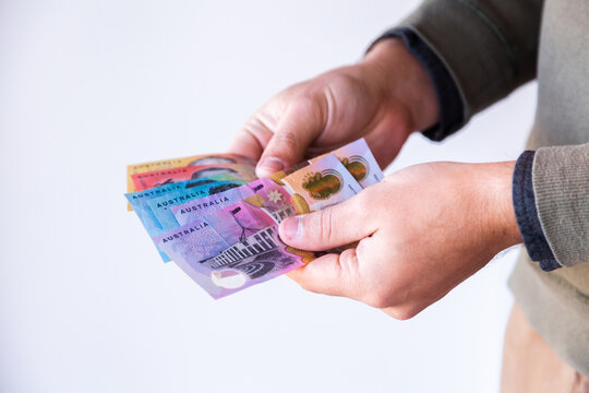Person's hands on white holding australian notes,cash for paying money