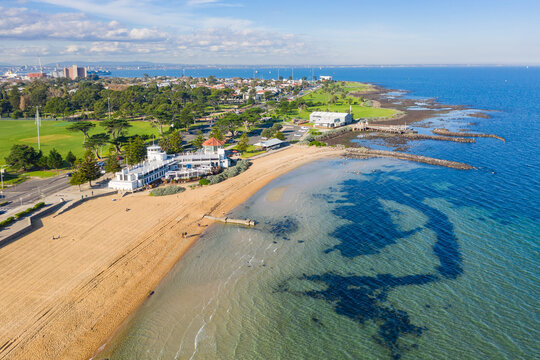 Aerial view of a bay side beach with surrounding parkland and sporting reserves