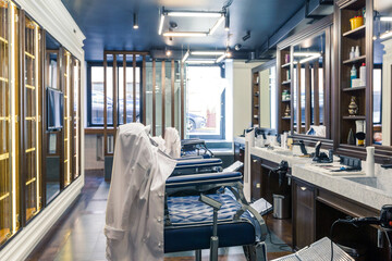 luxury barber shop interior, blue expensive furniture, wood trim, fashionable black ceiling, white robes on the backs of armchairs