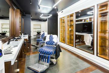 luxury barber shop interior, blue expensive furniture, wood trim, fashionable black ceiling, white robes on the backs of armchairs