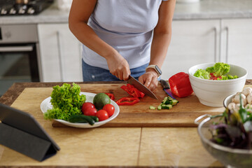 Beautiful smily handsome woman is preparing tasty fresh healthy salad at her kitchen at home