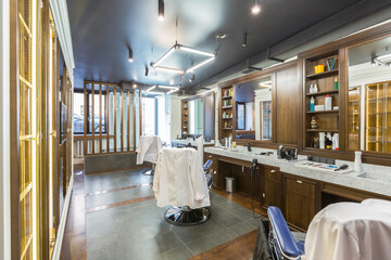 luxury barber shop interior, blue expensive furniture, wood trim, fashionable black ceiling, white robes on the backs of armchairs