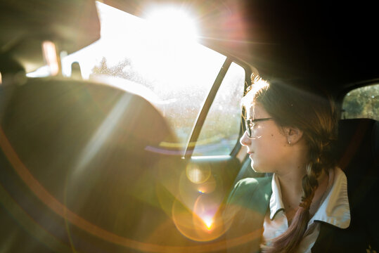 Teenage girl in school uniform traveling to school by car