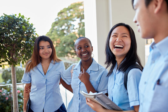 Group of secondary school students laughing together in corridor