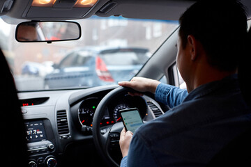 Man driving in his car looking down at mobile phone texting
