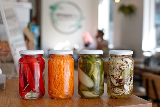 Variety of pickle jars lined up on counter in cafe