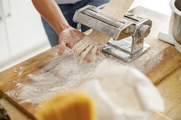 Beautiful smily handsome woman is preparing tasty fresh raw italian pasta at her kitchen at home