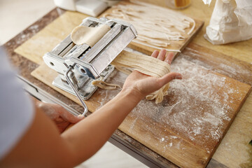Fototapeta na wymiar Beautiful smily handsome woman is preparing tasty fresh raw italian pasta at her kitchen at home