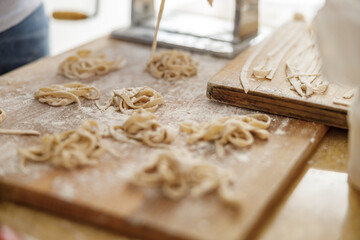 Beautiful smily handsome woman is preparing tasty fresh raw italian pasta at her kitchen at home