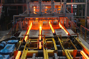 Red hot steel metal billets after molten steel casting.  Continuous casting machine. Background of...