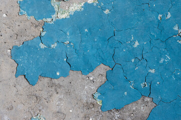 Blue peeling paint on the wall. Old concrete wall with cracked flaking paint. Weathered rough painted surface with patterns of cracks and peeling. High resolution texture for background and design.