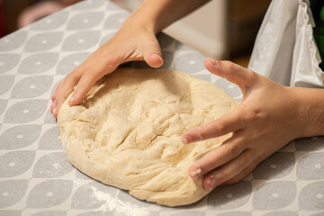 Two hands kneading cinnamon bun dough