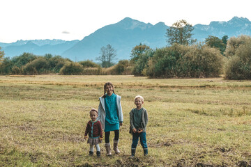 Fototapeta na wymiar Kinder stehen auf dem Feld vor den Bergen