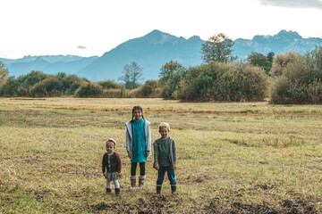 Fototapeta na wymiar Kinder stehen auf dem Feld vor den Bergen