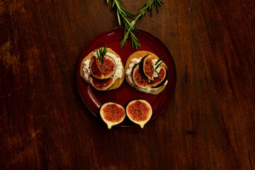 Fig dish with bread, rosemary and cream cheese on a plate