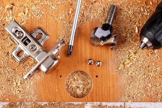 Installation of metal hinges with a soft close in a chipboard. Minor carpentry work when assembling furniture.