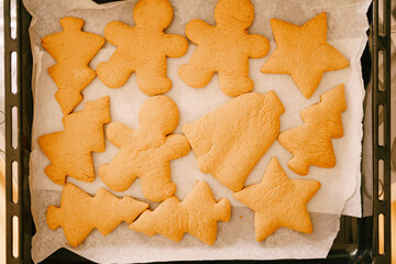 Freshly cooked gingerbread on a baking sheet from the oven, close-up of various shapes of cookies.