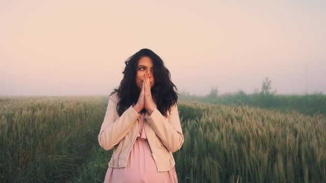 A pregnant girl walks across the field in an early cold morning in thick fog