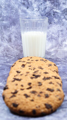American gluten free chocolate chip cookies with glass glass of vegetable milk on gray background. Chocolate chip cookies. Sweet pastries, dessert. Culinary background. Vertical photography.