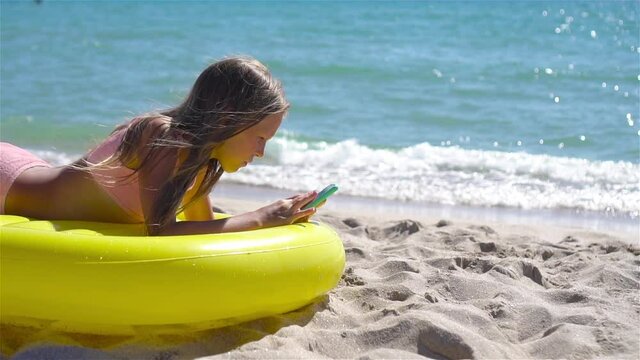 Adorable girl on inflatable air mattress on the beach