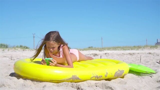 Adorable girl on inflatable air mattress on the beach