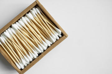 Eco-friendly cotton swabs. A cardboard box containing recyclable bamboo cotton buds on a gray surface. Zero waste concept. Eco product. Cosmetic sticks in a box. Wooden sticks for cleaning ears.
