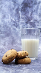 American gluten free chocolate chip cookies with glass glass of vegetable milk on gray background. Chocolate chip cookies. Sweet pastries, dessert. Culinary background. Vertical photography.