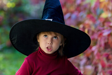 Little girl in witch costume making different faces on halloween party