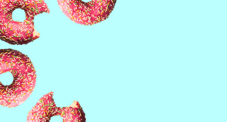 a large number of doughnuts in pink glaze and topping on a light turquoise background. pattern