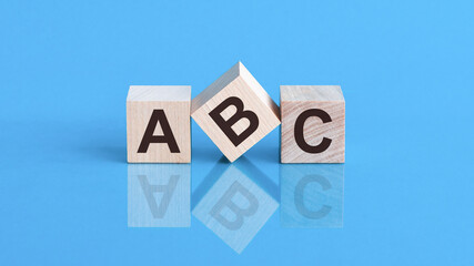 The text ABC is written on the cubes in black letters, the cubes are located on a blue glass surface.