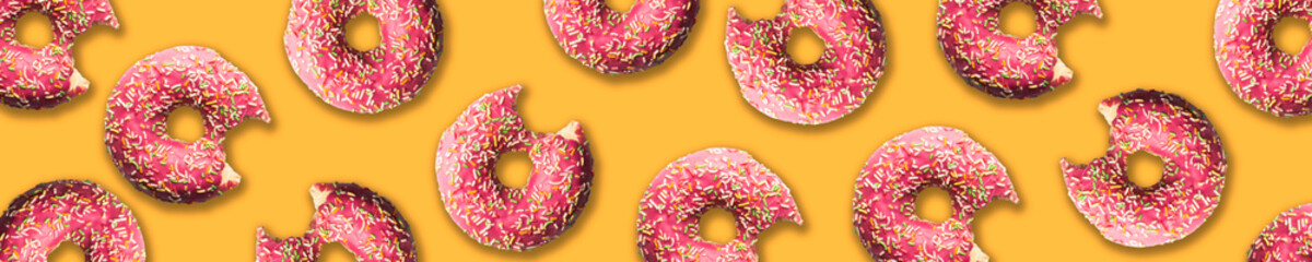 pattern. donuts in pink glaze and topping are laid out on a pink background.space for text