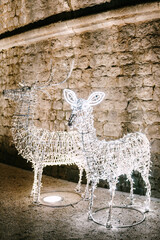The figure of Christmas deer is a metal frame covered with a white garland. Decoration of city streets for the New Year.