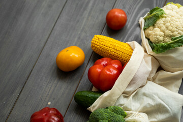 Zero waste concept. Pepper, tomato, corn, cucumber, broccoli, cauliflower in reusable shopping eco friendly cotton fabric bags. Vegetables in eco bag on a wooden table. Plastic free concept.