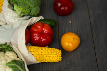 Zero waste concept. Pepper, tomato, corn, cucumber, broccoli, cauliflower in reusable shopping eco friendly cotton fabric bags. Vegetables in eco bag on a wooden table. Plastic free concept.