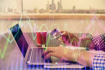 Double exposure of man hands holding a credit card and Forex graph drawing. Stock trading and digital fintech in Internet E-commerce concept.