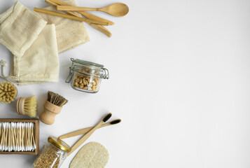 Zero waste kit. Set of eco friendly bamboo cutlery and cleaning brushes, mesh cotton bags, glass jars, loofah and box of cotton swabs. Natural and reusable items accessories on gray surface.