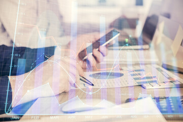 Double exposure of man's hands holding and using a digital device and forex graph drawing. Financial market concept.